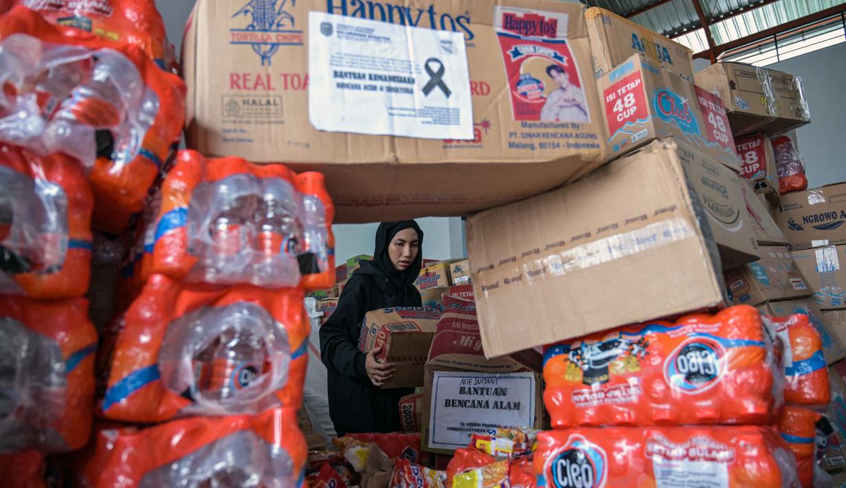 Seorang relawan mengemas perbekalan untuk dikirimkan ke daerah-daerah terdampak banjir di Badan Penanggulangan Bencana Daerah (BPBD) Sidoarjo, Provinsi Jawa Timur, pada Jumat 5 Desember 2025. Pemerintah Provinsi Jawa Timur akan memberangkatkan total 26,5 ton bantuan logistik untuk korban bencana di Sumatera Utara dan Aceh. (JUNI KRISWANTO/AFP)