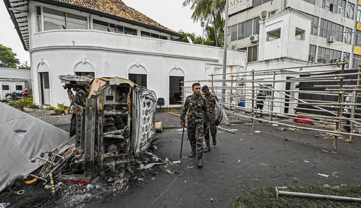 <p>Personel keamanan berjalan melewati kendaraan yang terbakar di dekat kediaman resmi mantan perdana menteri Sri Lanka Mahinda Rajapaksa 'Temple Trees', sehari setelah diterobos oleh para pengunjuk rasa di Kolombo pada 10 Mei 2022. PM Sri Lanka Mahinda Rajapaksa mengundurkan diri di tengah gelombang demonstrasi massal yang memprotes cara pemerintah menangani krisis ekonomi. (ISHARA S. KODIKARA / AFP)</p>
<p>&nbsp;</p>