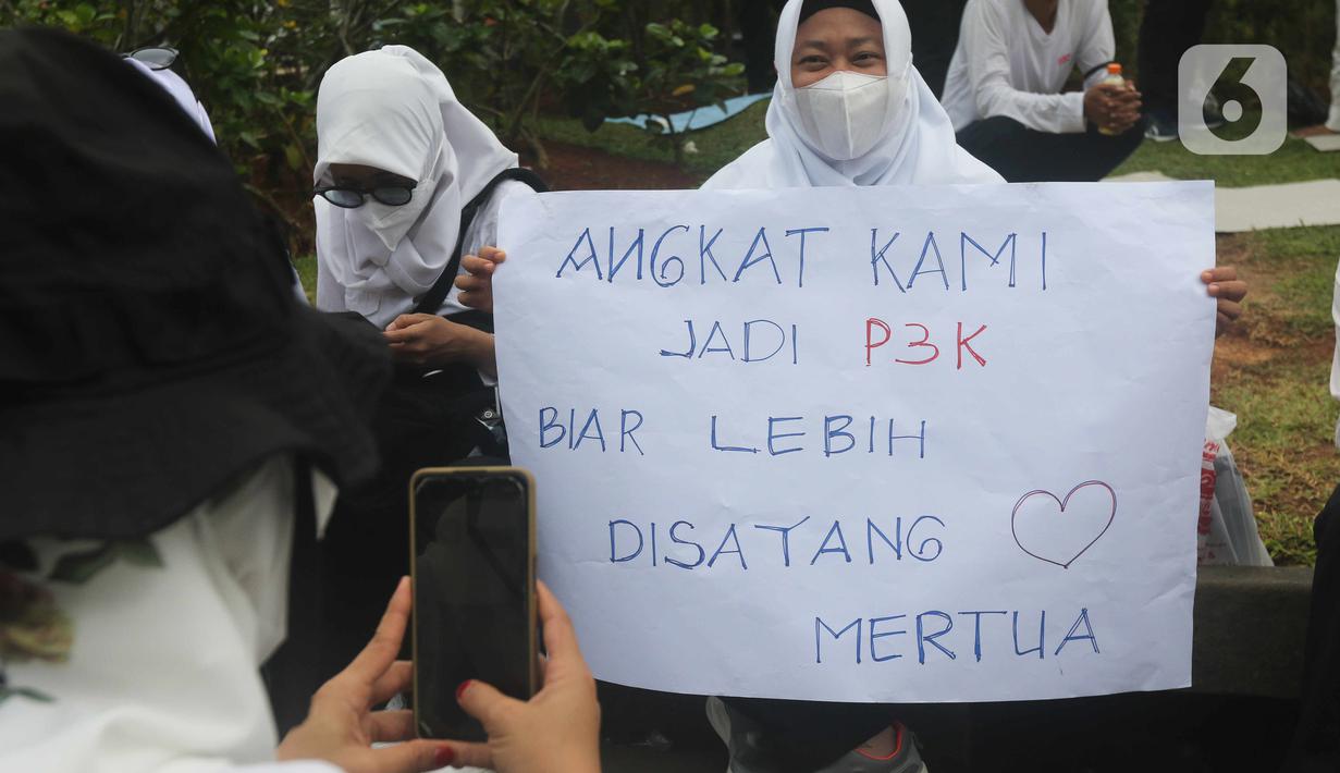 Massa dari Forum Komunikasi Nakes dan Non-Nakes Indonesia (FKHN Indonesia) membawa poster tuntutan saat menggelar aksi di kawasan Patung Kuda, Jakarta Pusat, Kamis (22/9/2022). Mereka menuntut Presiden Joko Widodo segera menerbitkan Peraturan Presiden (PP) khusus yang mengatur honorer nakes dan nonnakes bisa diangkat menjadi Aparatur Sipil Negara (ASN). (Liputan6.com/Herman Zakharia)