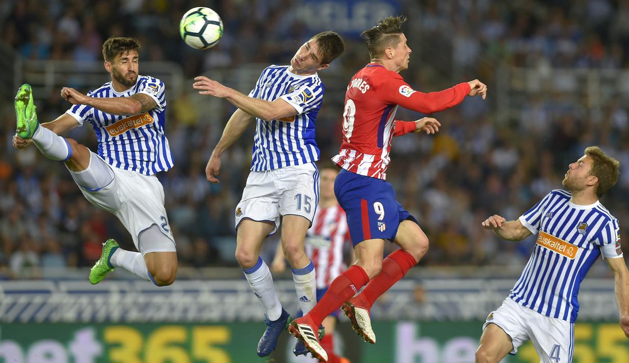 Striker Atletico Madrid, Fernando Torres, duel udara dengan bek Real Sociedad, Aritz Elustondo, pada laga La Liga di Stadion Municipal de Anoeta, Kamis (19/4/2018). Real Sociedad menang 3-0 atas Atletico Madrid. (AFP/Ander Gillenea)