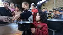 Situasi ini menempatkan pengungsi Palestina berada di ambang kelaparan. Tampak dalam foto, anak-anak pengungsi Palestina menunggu untuk menerima makanan dari dapur amal di kamp pengungsi Nuseirat, Jalur Gaza Tengah pada 13 April 2026. (Eyad Baba/AFP)
