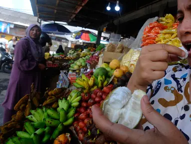 Warga mencicipi buah salju di Pasar Candi Kuning, Bedugul, Bali, Senin (24/04/2023). Buah ini sempat viral di media sosial beberapa waktu lalu. (merdeka.com/Arie Basuki)