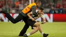 Petugas mengamankan suporter usai leg pertama semifinal Liga Champions antara Bayern Munchen vs Real Madirid di Allianz Arena, Rabu (25/4). Beberapa suporter nekad masuk lapangan mendekati pemain untuk diajak selfie dan berpelukan. (AFP/Odd ANDERSEN)