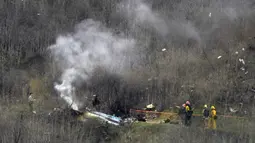 Sejumlah petugas berusaha mengevakuasi korban jatuhnya helikopter di Calabasas, California, Minggu (26/1/2020). Legenda NBA, Kobe Bryant, menjadi salah satu korban tewas pada kecelekaan helikopter berjenis Sikorsky S-76B itu. (AP/Mark J. Terrill)