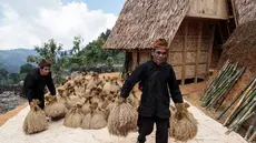 Warga bersiap meletakkan tumpukan padi di lumbung kayu tradisional di atas panggung, yang dikenal masyarakat setempat sebagai leuit, dalam perayaan panen Seren Taun di Sukabumi, Jawa Barat, pada Minggu 5 Oktober 2025. (Aditya AJI/AFP)