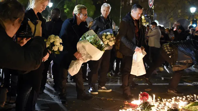 Grup band U2 Bono, Adam Clayton , Larry Mullen Jr  dan The Edge meletakkan karangan bunga di trotoar di depan gedung pertunjukan Bataclan Theatre, salah satu tempat serangan teroris di Paris, Perancis, Sabtu (14/11). (AFP PHOTO / FRANCK FIFE)