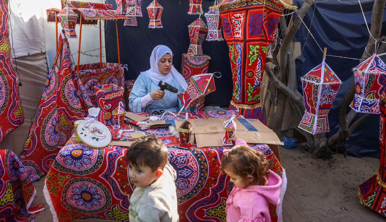 Lentera ini sering dibuat oleh perajin lokal di Gaza, seperti di Khan Younis, dan Kota Gaza. Tampak dalam foto, Rehan Hazem Sharab, seorang pengungsi Palestina berusia 32 tahun, membuat lampion buatan tangan dari kotak-kotak bantuan yang tersisa sebagai persiapan menyambut bulan suci Ramadan yang dimulai pada 17 Februari, di luar tendanya di lingkungan Al-Mawasi, Khan Younis, di Jalur Gaza selatan pada Sabtu 7 Februari 2026. (Bashar Taleb/AFP)