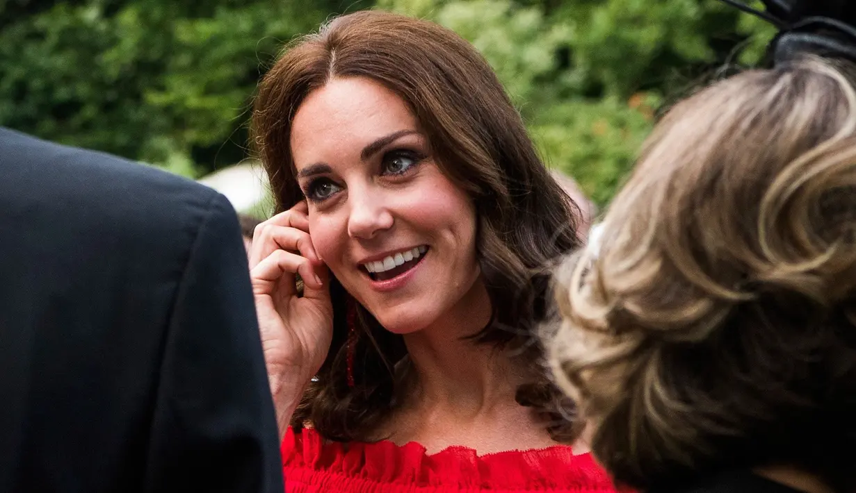 Kate Middleton berbincang dengan para tamu saat menghadiri acara 'Queen's Birthday Garten Party' di kediaman duta besar Inggris di Berlin, Rabu (19/7). Dalam acara itu, Kate Middleton tampil  anggun dalam balutan gaun merah (Matthias Nareyek/Pool via AP)