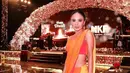 Yuni Shara hadir mengenakan baju khas Bollywood didominasi warna orange kemerahan. Dari atasan tanpa lengan crop top yang mengekspos perut ratanya.  [@yunishara36]