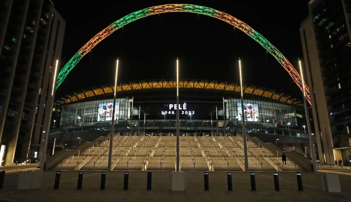 Lengkungan Stadion Wembley menyala dalam warna Brasil dan layar menampilkan gambar Pele setelah pengumuman bahwa mantan pemain sepak bola Brasil itu meninggal dunia, London, Inggris, 29 Desember 2022. Edson Arantes do Nascimento atau yang dikenal sebagai Pele, raja sepak bola Brasil yang menang rekor tiga Piala Dunia dan menjadi salah satu tokoh olahraga paling berwibawa abad lalu, meninggal pada usai 82 tahun di di Sao Paulo. (Kieran Cleeves/PA via AP)