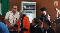 Korban ledakan bom di Jalan MH Thamrin pada Januari 2016, Ipda Denny Mahieu menyalami terdakwa Aman Abdurrahman di PN Jakarta Selatan, Jumat (23/2). Dalam sidang, Denny menceritakan kembali peristiwa dua tahun lalu itu. (Liputan6.com/Ady Anugrahadi)