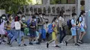 Siswa sekolah dasar mengenakan masker untuk melindungi diri dari penyebaran COVID-19 dan berjalan ke gerbang sekolah di Taipei, Taiwan, Rabu (1/9/2021). Seluruh sekolah di Taiwan kembali dibuka untuk tahun ajaran baru setelah ditutup akibat pandemi COVID-19. (AP Photo/Chiang Ying-ying)