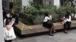 Pusat perbelanjaan menerapkan langkah social distancing atau jaga jarak sosial dengan memberikan tanda silang di area tempat duduk publik di wilayah Bugis Singapura, 28 Maret 2020. Warga di Singapura yang melanggar perintah jaga jarak akan dikenakan denda sekitar Rp 1112 juta. (Xinhua/Then Chih Wey)