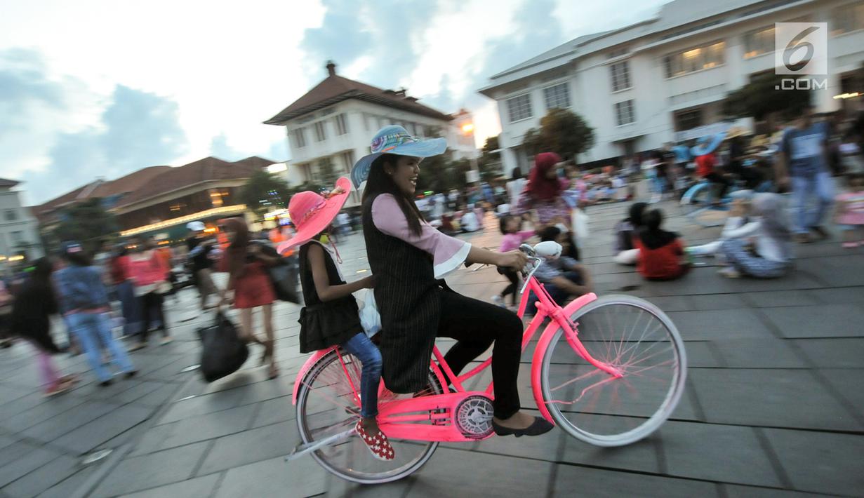 Pengunjung bermain sepeda yang disewakan di kawasan Kota Tua, Jakarta, Selasa (27/6). Pengunjung bisa menikmati Kota Tua, dari menyewa sepeda ontel dengan berbagai warna sampai berfoto bersama dengan manusia patung. (Liputan6.com/Yoppy Renato)