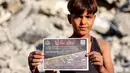 Seorang anak laki-laki memegang salah satu selebaran yang dijatuhkan oleh militer Israel di Kota Gaza, yang menyerukan evakuasi ke selatan menuju al-Mawasi, pada 9 September 2025. (Omar AL-QATTAA/AFP)