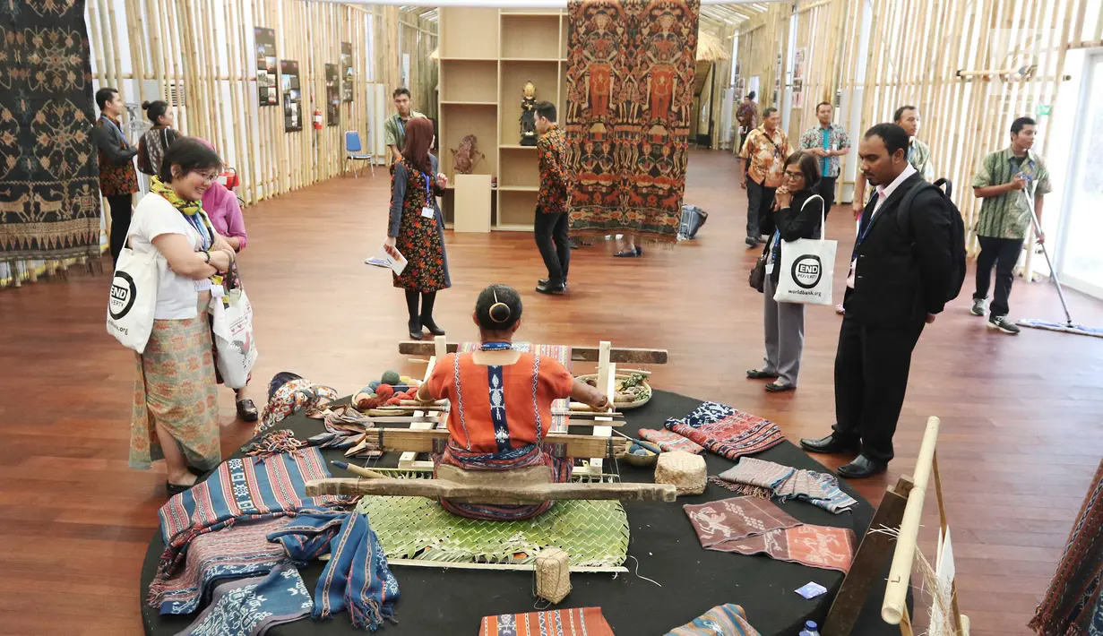 Peserta pertemuan tahunan IMF-Bank Dunia melihat proses penenunan di Paviliun Indonesia, Bali, Senin (8/10). Selain BUMN, pameran ini juga didukung oleh KKP, Kementerian ESDM, Badan Ekonomi Kreatif, Kominfo dan Kemenkeu. (Liputan6.com/Angga Yuniar)