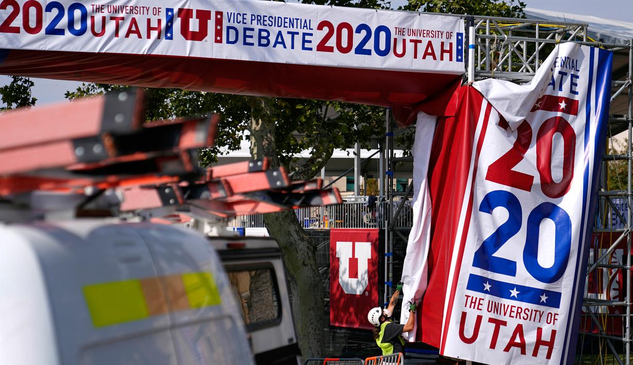 Para pekerja menggantung spanduk saat persiapan lanjutan untuk debat calon wakil presiden AS di luar Kingsbury Hall, Universitas Utah di Salt Lake City, Senin (5/10/2020). Debat cawapres petahana Mike Pence dan Senator California Kamala Harris akan digelar pada 7 Oktober. (AP Photo/Patrick Semansky)