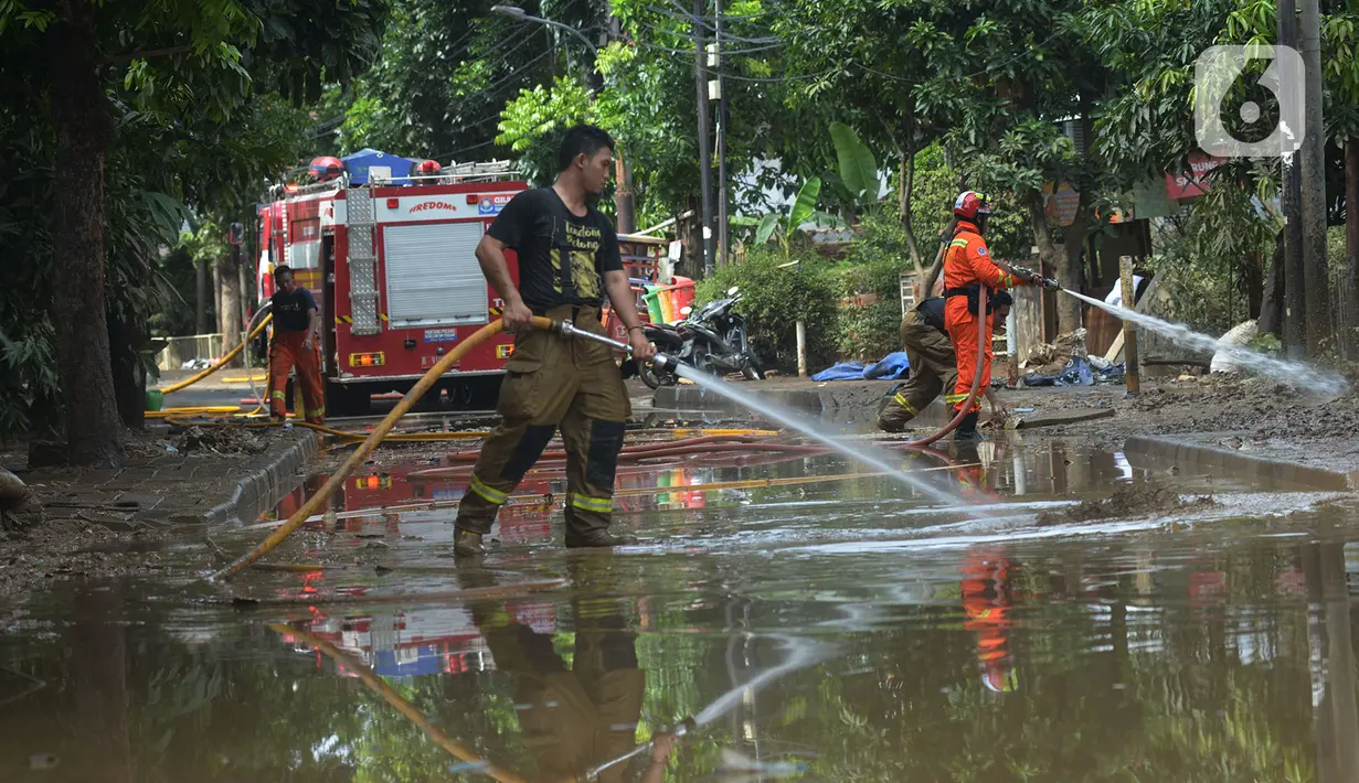 Petugas pemadam kebakaran menyemprotkan air untuk membersihkan lumpur sisa banjir di Kawasan Bukit Duri, Jakarta, Sabtu (4/1/2020). Meski banjir sudah mulai surut, jalan-jalan dan permukiman warga masih tertutup lumpur tebal. (merdeka.com/Imam Buhori)