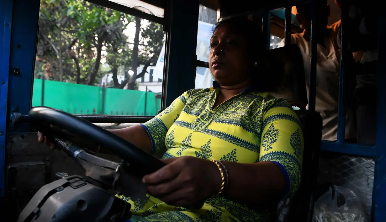 Pratima Poddar saat mengendarai bus di Kolkata, India (8/3). Pratima Poddar 42 tahun merupakan satu-satunya sopir bus umum perempuan di Kolkata. (AFP Photo/Dibyangshu Sarkar)