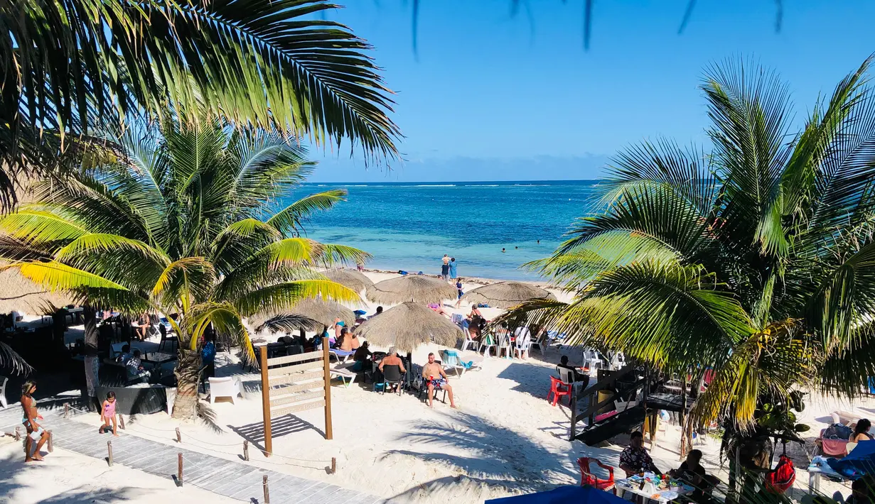 Wisatawan menikmati pantai di Puerto Morelos, negara bagian Quintana Roo, Meksiko (14/2). Puerto Morelos adalah sebuah kota dan pelabuhan di Quintana Roo, negara bagian paling timur Meksiko, di Semenanjung Yucatán. (AFP Photo/Daniel Slim)
