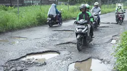 Pengendara sepeda motor berusaha menghindari jalan yang rusak di Jalan Raya Gas Alam, Depok, Jawa Barat, Selasa (7/5). Kondisi jalan yang tidak kunjung diperbaiki tersebut menjadi kubangan air setiap hujan serta berbahaya bagi keselamatan pengguna jalan. (Liputan6.com/Immanuel Antonius)
