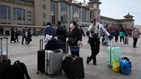 Penumpang membawa tas menunggu kereta di luar pintu masuk stasiun kereta api Beijing di ibu kota China (7/1/2023). Ketika migrasi tahunan dimulai dengan orang-orang yang kembali ke kampung halaman mereka untuk perayaan Tahun Baru Imlek. (AFP/Wang Zhao)