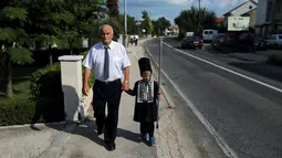 Seorang kakek mengantar cucunya untuk mengikuti turnamen tradisional Alka di desa Vuckovici, Kroasia, Minggu (23/8/2015). Turnamen ini Agustus memperingati kemenangan Kroasia atas pemerintahan Turki Ottoman. (REUTERS/Antonio Bronic) 