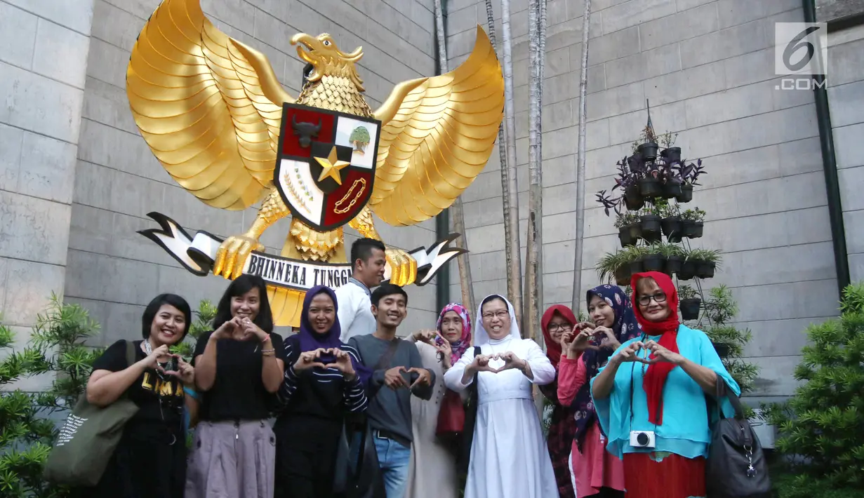 Sejumlah umat muslim foto bersama di depan Garuda Pancasila di Gereja Katedral, Jakarta, Jumat (1/6). Kegiatan tersebut digelar komunitas Kerja Bakti Demi Negeri sambil buka puasa bersama. (Liputan6.com/Arya Manggala)