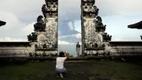 Turis asing foto di depan Gunung Agung yang meletus di Kabupaten Karangasem, Bali, (27/11). Sebelumnya, Gunung Agung telah mengalami erupsi sejak Sabtu (25/11) sore. (AP Photo / Firdia Lisnawati)