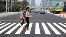 Pejalan kaki sedang menyebrang di pelican crossing di kawasan Thamrin, Jakarta, Minggu (29/7). Pelican crossing di kawasan Thamrin sudah bisa di gunakan pengganti JPO yang akan dibongkar. (Liputan6.com/Herman Zakharia)