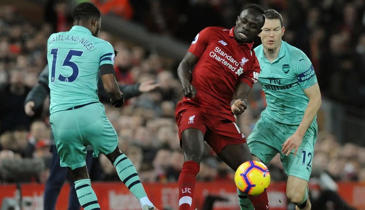 Penyerang Liverpool, Sadio Mane berebut bola dengan pemain Arsenal, Ainsley Maitland-Niles pada lanjutan Liga Inggris di Anfield Stadium (29/12). Kemenangan ini, membuat Liverpool  kokok di puncak klasemen dengan poin 54. (AP Photo/Rui Vieira)