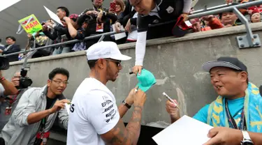 Pembalap Mercedes Lewis Hamilton memberi tanda tangan disebuah topi penggemarnya jelang Grand Prix F1 di Sirkuit Suzuka, Jepang (5/10). F1 GP Jepang akan digelar pada tanggal 8 Oktober mendatang. (AP Photo/Eugene Hoshiko)