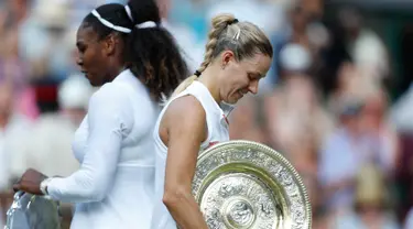 Petenis Jerman, Angelique Kerber (kanan) membawa trofi usai mengalahkan petenis AS, Serena Williams pada final tunggal putri kejuaraan Tenis Wimbledon 2018 di London, (14/7). Kerber menang atas Williams 6-3,6-3. (AP Photo/Nic Bothma)