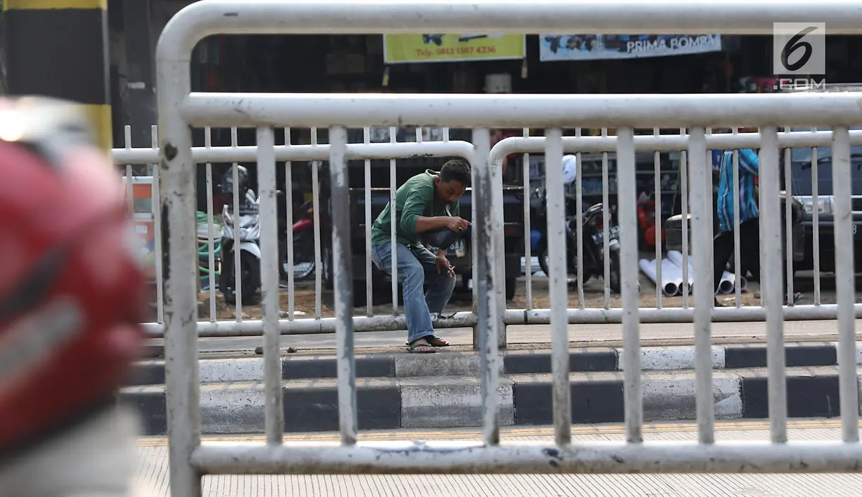 Seorang pria menerobos pagar pembatas jalan di kawasan Pasar Minggu, Jakarta, Kamis (5/4). Kondisi Jembatan Penyeberangan Orang (JPO) yang tak kunjung diperbaiki membuat warga nekat menyeberang lewat celah pagar pembatas. (Liputan6.com/Immanuel Antonius)