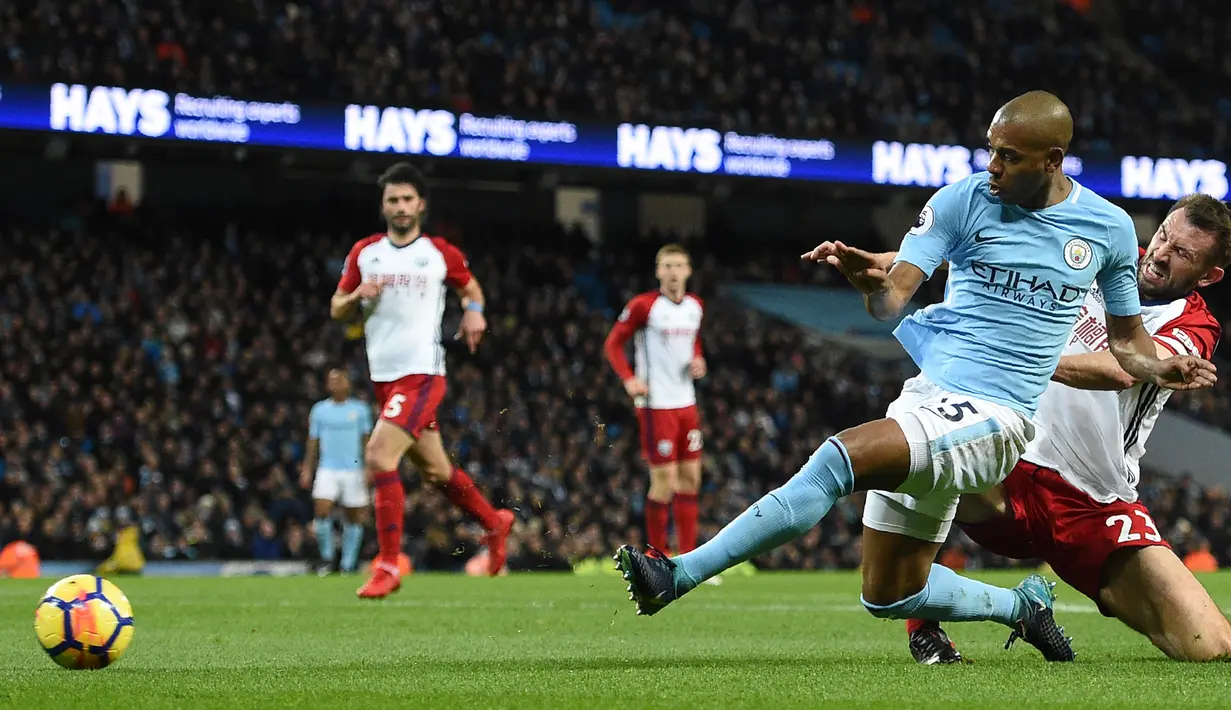 Gelandang Manchester City, Fernandinho melakukan tendangan dengan kawalan pemain West Bromwich Albion Gareth McAuley pada laga pekan ke-25 Premier League di Etihad Stadium, Kamis (1/2). Manchester City membenamkan West Bromwich 3-0. (Oli SCARFF/AFP)