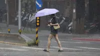 Seorang wanita berjalan di tengah hujan saat Topan Koinu yang menyebabkan banjir besar di Hongkong bergerak mendekati Taiwan di Taipei. (AP/Chiang Ying-ying)