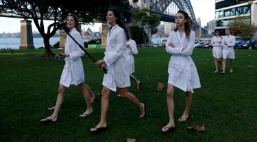 Sejumlah model berjalan dengan tongkat selfienyadi samping jembatan Sydney Harbour Bridge dalam perjalanan ke lokasi catwalk acara Manning Cartell di Australia Fashion Week, 17 Mei 2016. (REUTERS/Jason Reed)