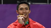 Pebulu tangkis Indonesia, Jonatan Christie mengigit medali emas usai upacara penghargaan cabang olahraga badminton Asian Games 2018 di Jakarta, Selasa (28/8). Jonatan menang atas wakil Chinese Taipei, Chou Tienchen.  (AFP Photo/Sonny Tumbelaka)