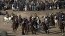 Seorang peserta membawa bangkai yang diperebutkan peserta lainnya saat pertandingan Buzkashi di Mazar-i-Sharif, Afghanistan (20/12). Pemain harus membawa bangkai di sekitar bendera atau penanda di salah satu ujung lapangan. (AFP/Farshad Usyan)