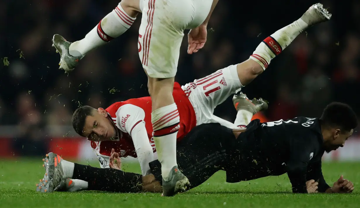 Pemain Arsenal Lucas Torreira (atas) berbenturan dengan pemain Manchester United Jesse Lindgard pada pertandingan lanjutan Liga Inggris di Emirates Stadium, London, Rabu (1/1/2020). Arsenal menang 2-0. (AP Photo/Matt Dunham)