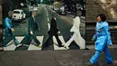 Seorang wanita melewati sebuah gambar nyata saat kegiatan untuk memecahkan rekor dunia dengan jumlah terbesar orang mengenakan pakaian dan bergaya seperti  The Beatles di sebuah taman di Mexico City, Meksiko 28 November 2015. (AFP PHOTO/ALFREDO ESTRELLA)