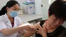 Seorang wanita mendapat suntikan vaksin anti rabies di Pusat Pengendalian dan Pencegahan Penyakit di Huaibei, Selasa (24/7). Salah satu produsen vaksin terbesar di negara itu diketahui memalsukan data produksi dalam pembuatan vaksin rabies. (AFP)