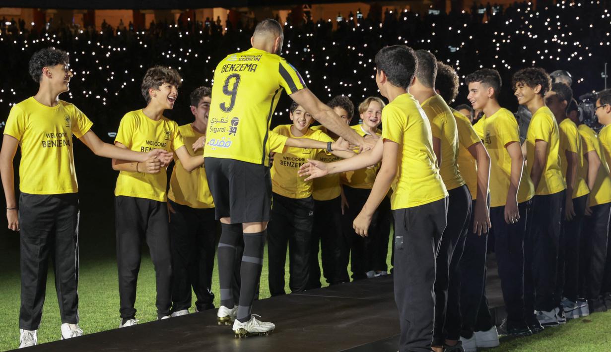 <p>Karim Benzema bersalaman dengan fans cilik dalam perkenalan sebagai pemain baru Al Ittihad. (AFP Photo)</p>