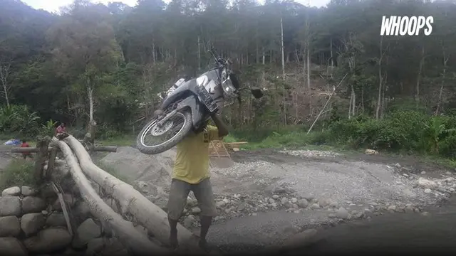 Kondisi jembatan yang rapuh tenyata membuat Jhon harus mengangkat motornya saat sebrangi sungai.