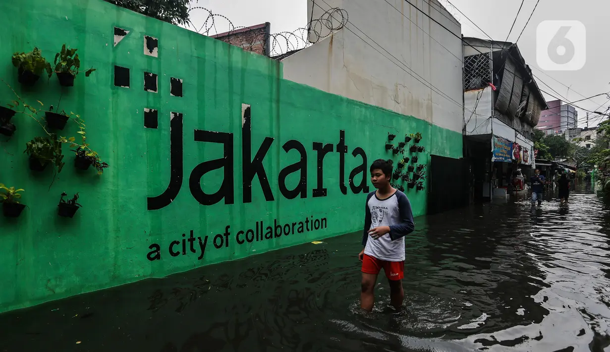 Seorang remaja melintasi banjir yang merendam lingkungan rumah tempat tinggal mereka di kawasan kecamatan Kebayoran Baru, Jakarta, Senin (25/01/2021). Hujan deras yang mengguyur Jakarta hari ini, Senin (25/1) menyebabkan terjadinya banjir di kawasan permukiman tersebut. (Liputan6.com/Johan Tallo)