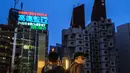 Orang-orang memotret Nakagin Capsule Tower (kanan), sebuah bangunan perumahan dan perkantoran serba guna di distrik Ginza Tokyo, 6 April 2022. Menara yang selesai pada tahun 1972 dan dirancang oleh arsitek terkenal Kisho Kurokawa itu adalah sebuah landmark dari gerakan Metabolisme. (Philip FONG/AFP)