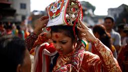 Seorang bocah dipakaikan mahkota saat perayaan Gaijatra Festival atau Festival Sapi di Kathmandu, Nepal, Jumat (19/8). Sapi dianggap sebagai binatang suci di Nepal yang membantu jiwa untuk mencapai surga. (REUTERS/ Navesh Chitrakar)
