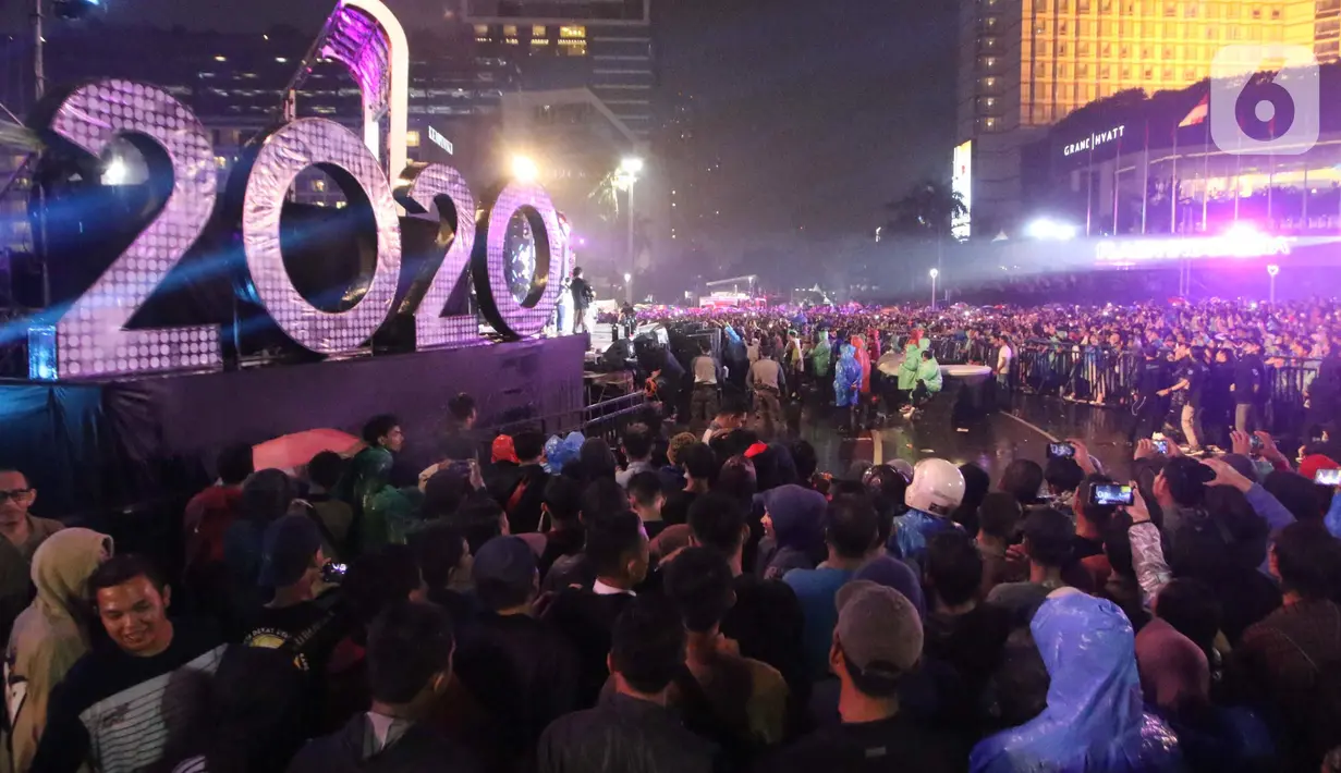 Warga berkerumun menikmati salah satu panggung hiburan di Bundaran Hotel Indonesia, Jakarta, Selasa (31/12/2019). Meski Jakarta diguyur hujan sejak Selasa (31/12) sore, warga tetap antusias melewati malam pergantian tahun 2019 menuju 2020 di kawasan Bundaran HI Jakarta. (Liputan6.com/Angga Yuniar)