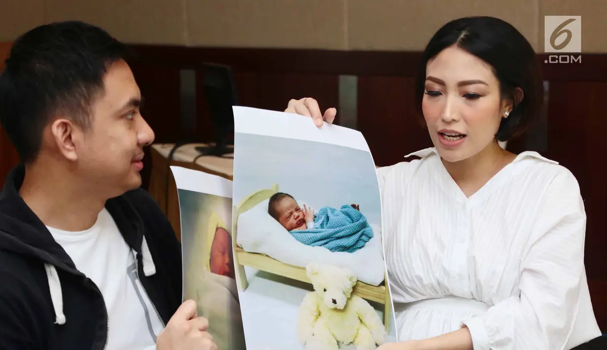 Ayu Dewi dan suami memperlihatkan foto anak kedua mereka saat jumpa pers di Rumah Sakit kawasan Pondok Indah, Jakarta, Senin (10/7). Ayu Dewi berharap anaknya nanti memiliki akhlak yang indah seperti Nabi Muhammad SAW. (Liputan6.com/Herman Zakharia)