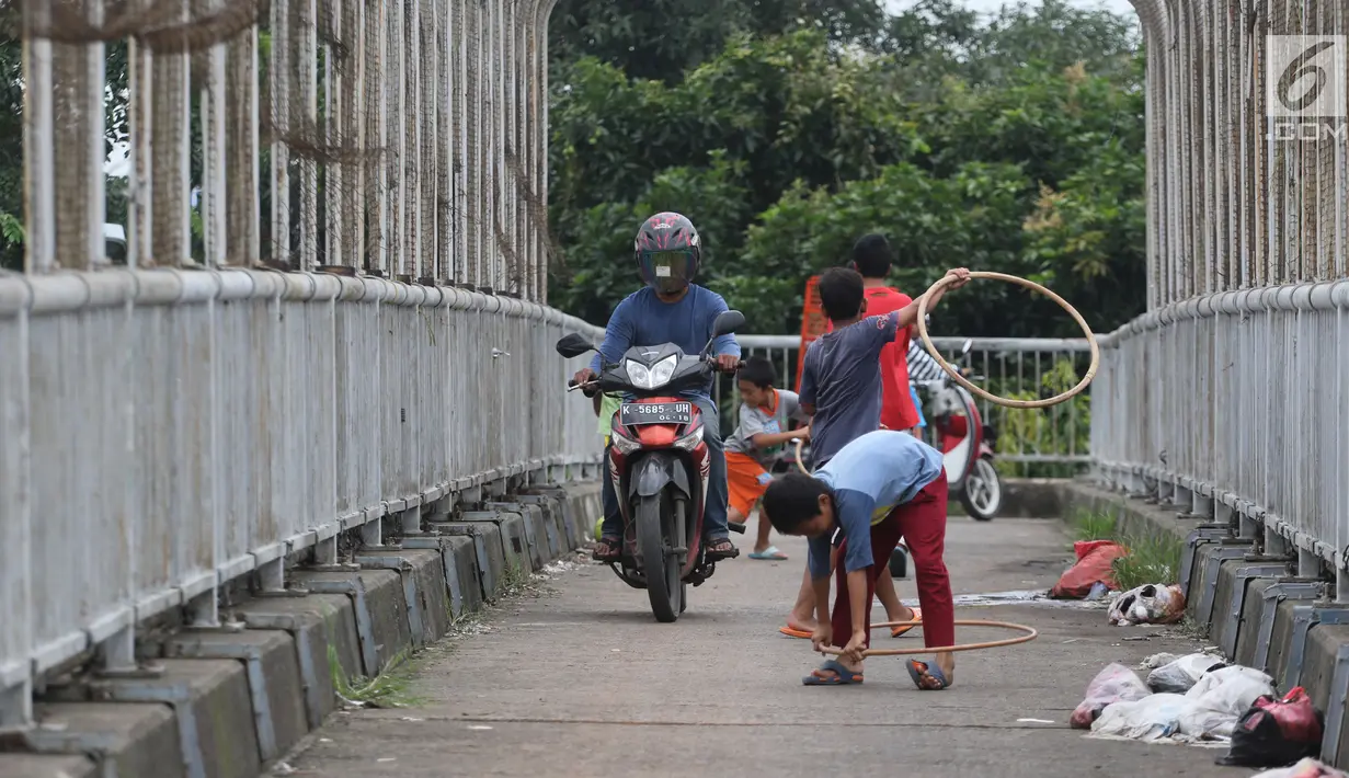 Pengendara motor melintas di samping anak-anak yang bermain di JPO kawasan Cikunir, Bekasi Barat, Senin (12/3). JPO bukan lagi dipenuhi oleh pejalan kaki, tapi berubah fungsi menjadi lahan bermain dan jalan pintas pemotor. (Liputan6.com/Arya Manggala)
